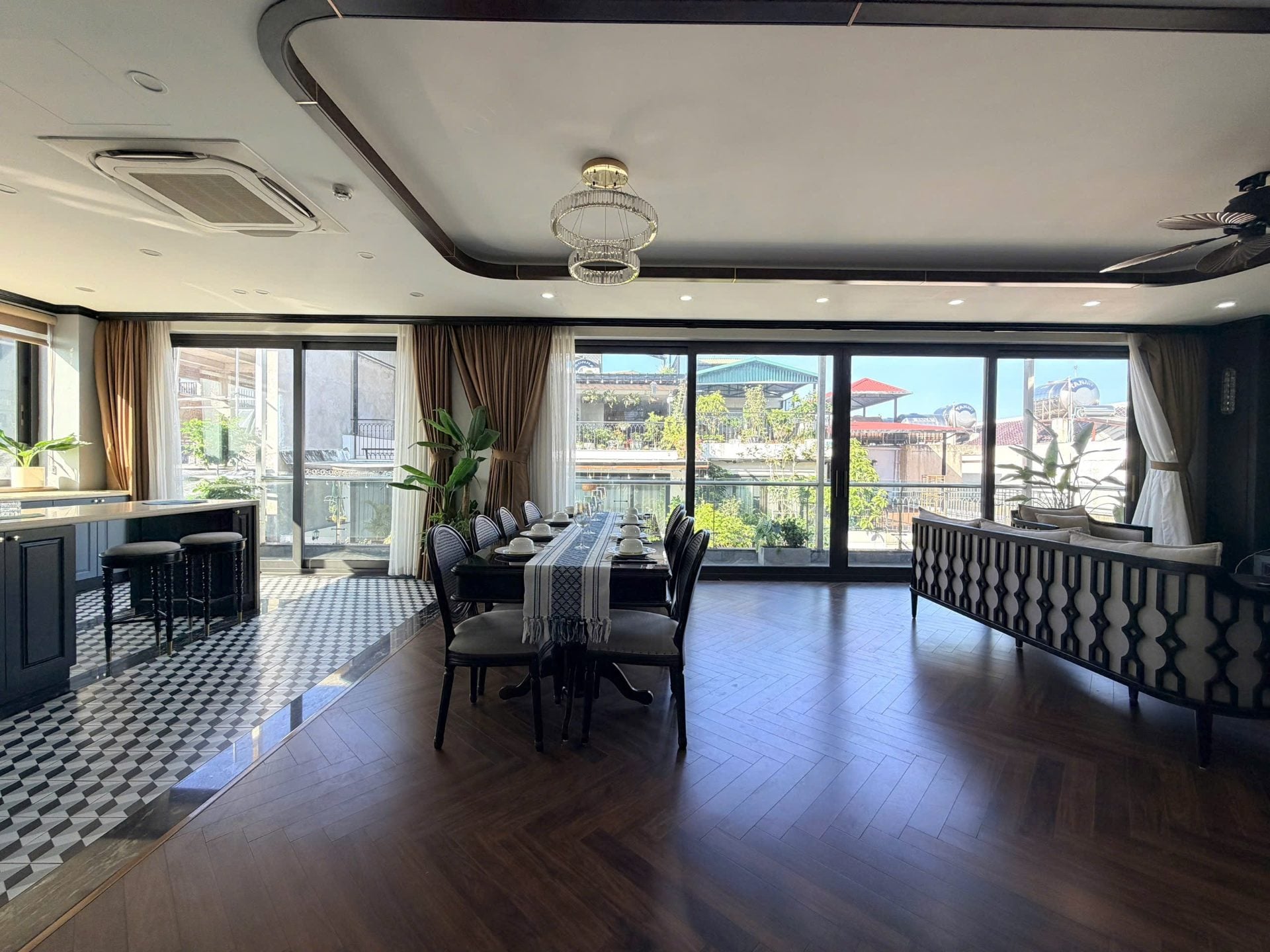 A large living and dining room with a ceiling air conditioner, a long dining table and tall windows over a balcony