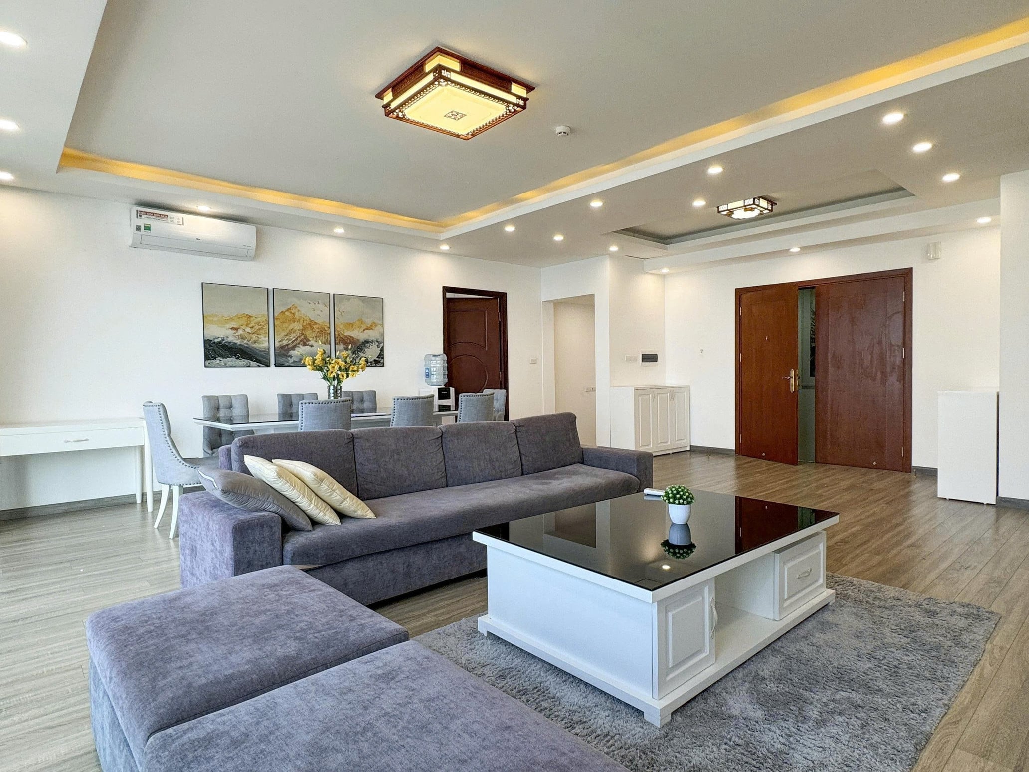 Open-plan living and dining room with a grey sofa, a white coffee table and wood-effect flooring