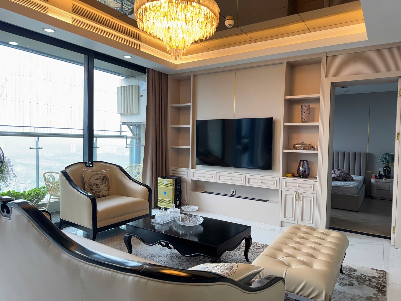 A furnished living room with armchairs and a dining table by tall windows