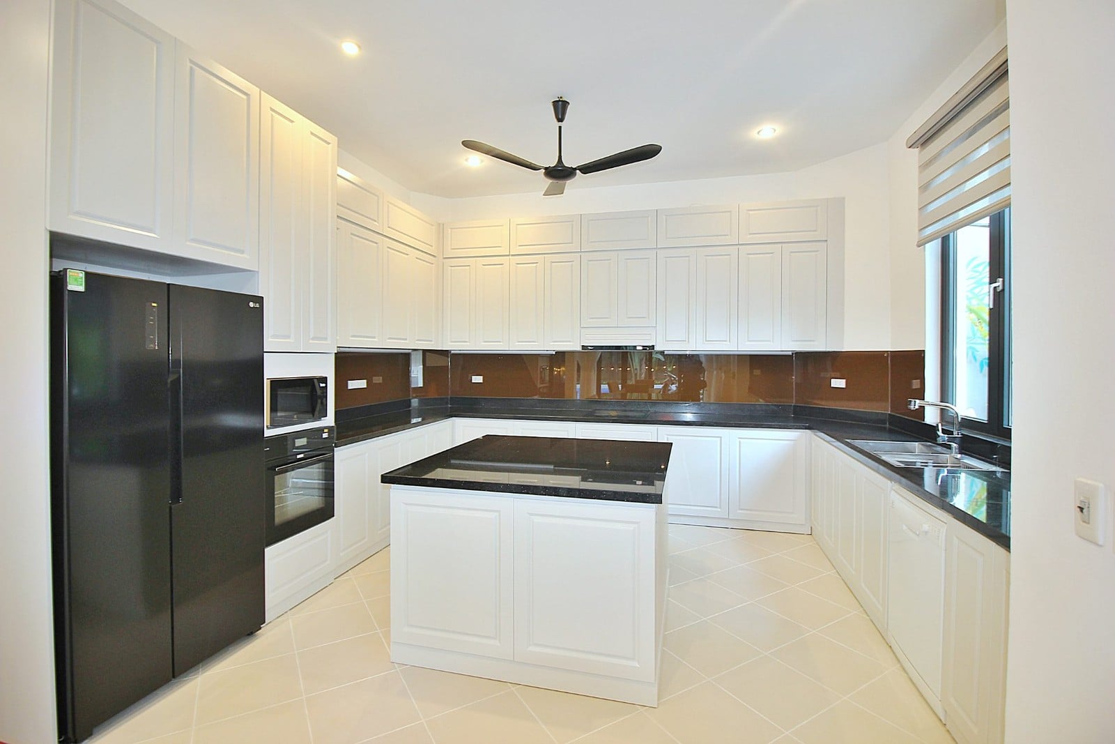 A clean white kitchen with an island in a villa