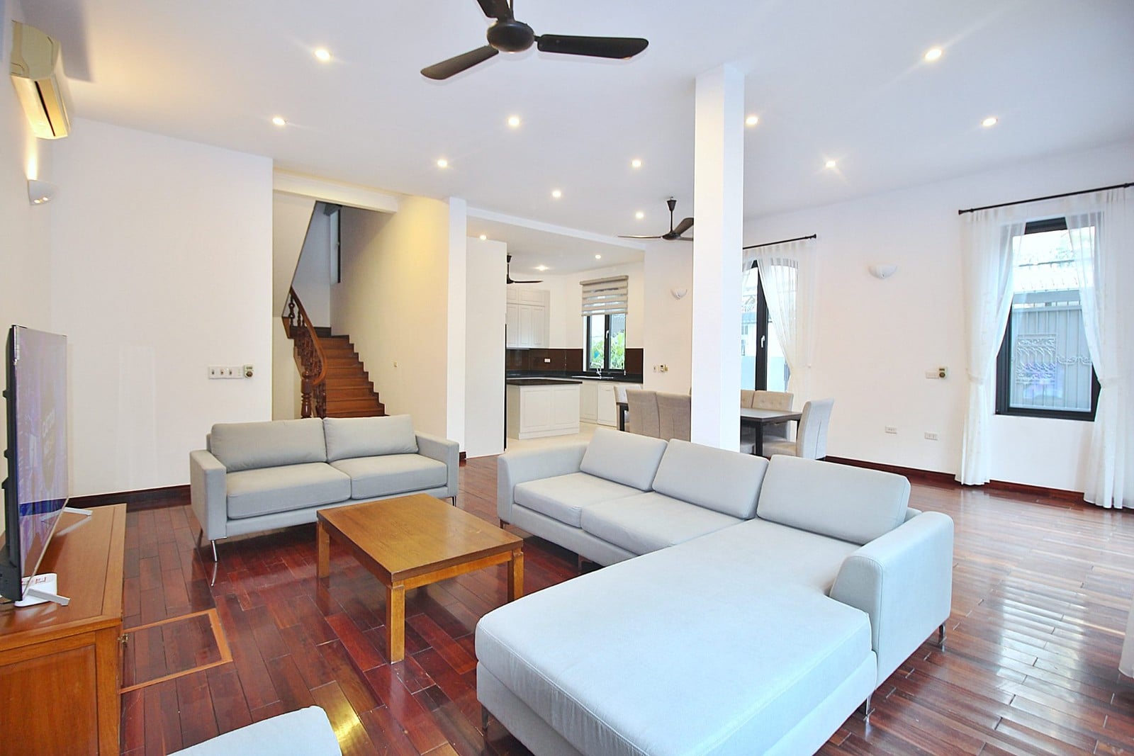 A bright villa living room with timber floors and grey sofas