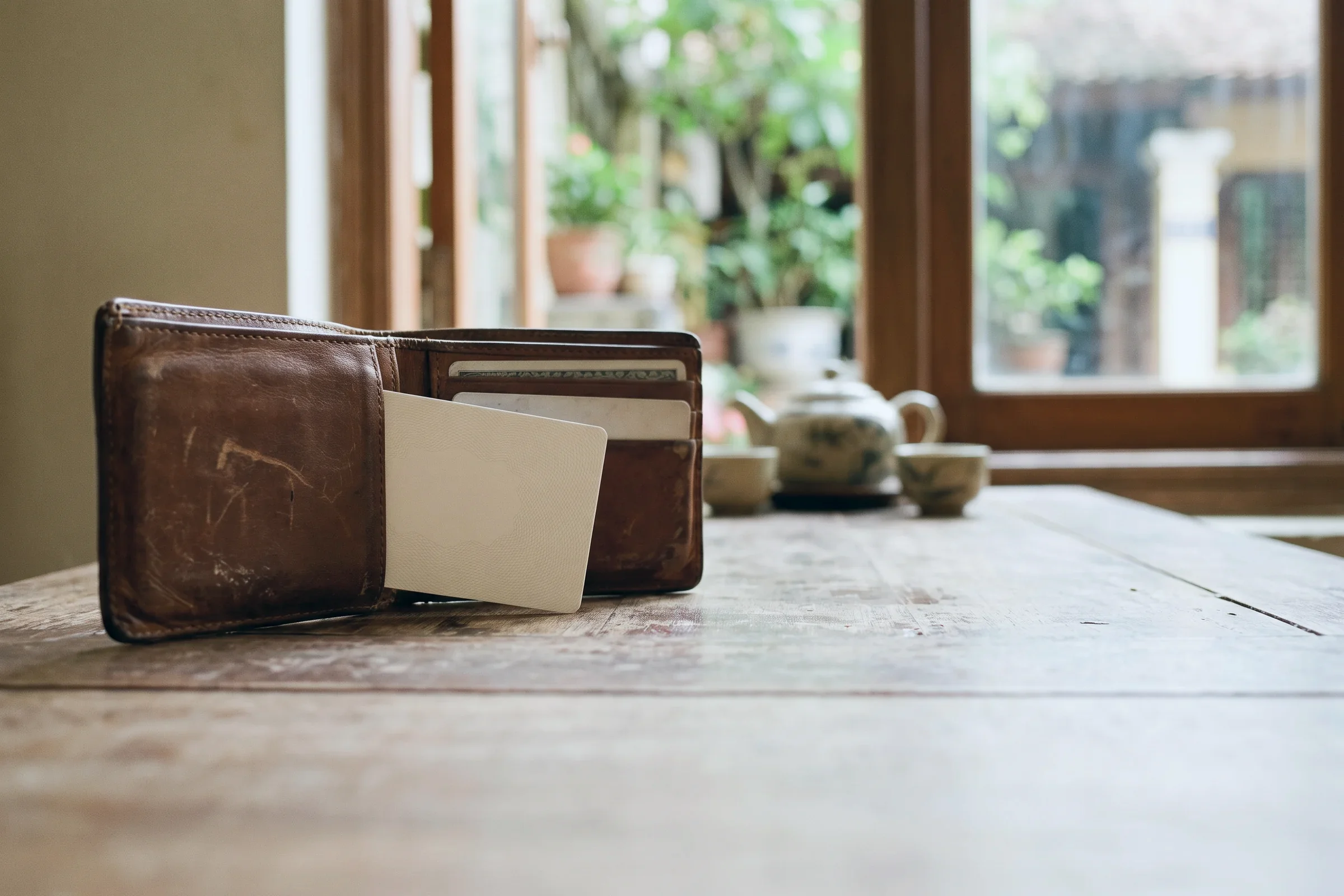 A blank card tucked into a leather wallet on a table by a window
