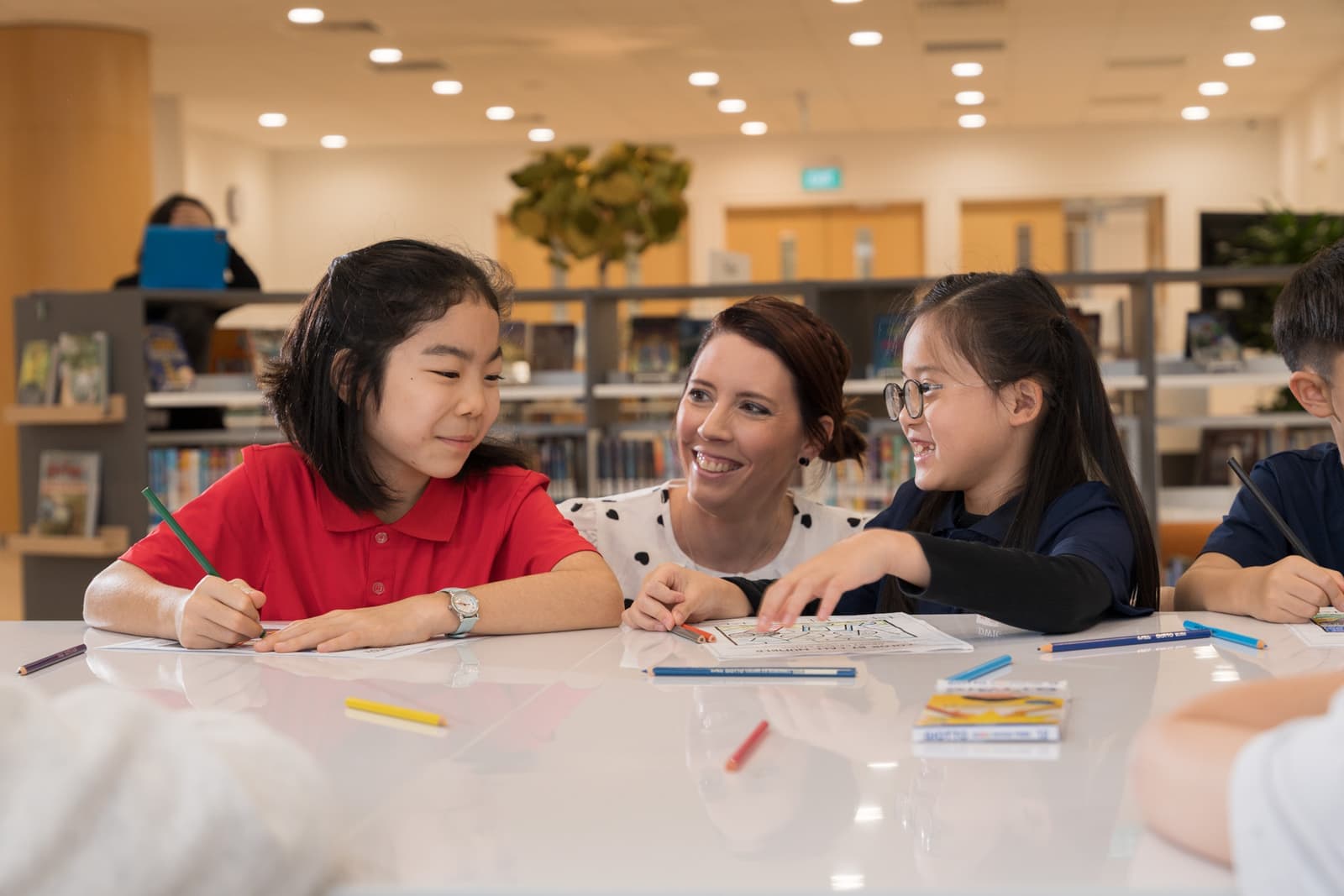 A teacher working with young students in the library