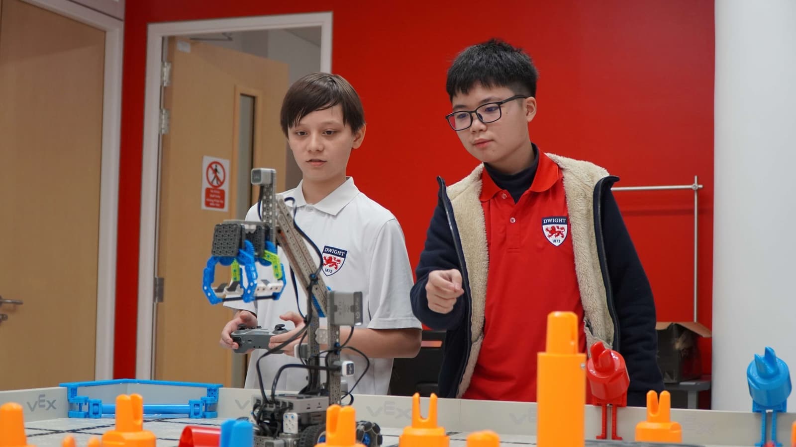 Two students driving a robot on a competition field