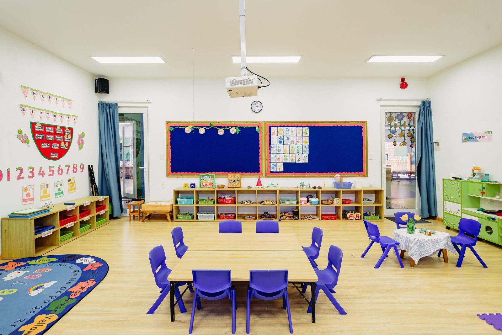 An early years classroom with small tables and a reading rug