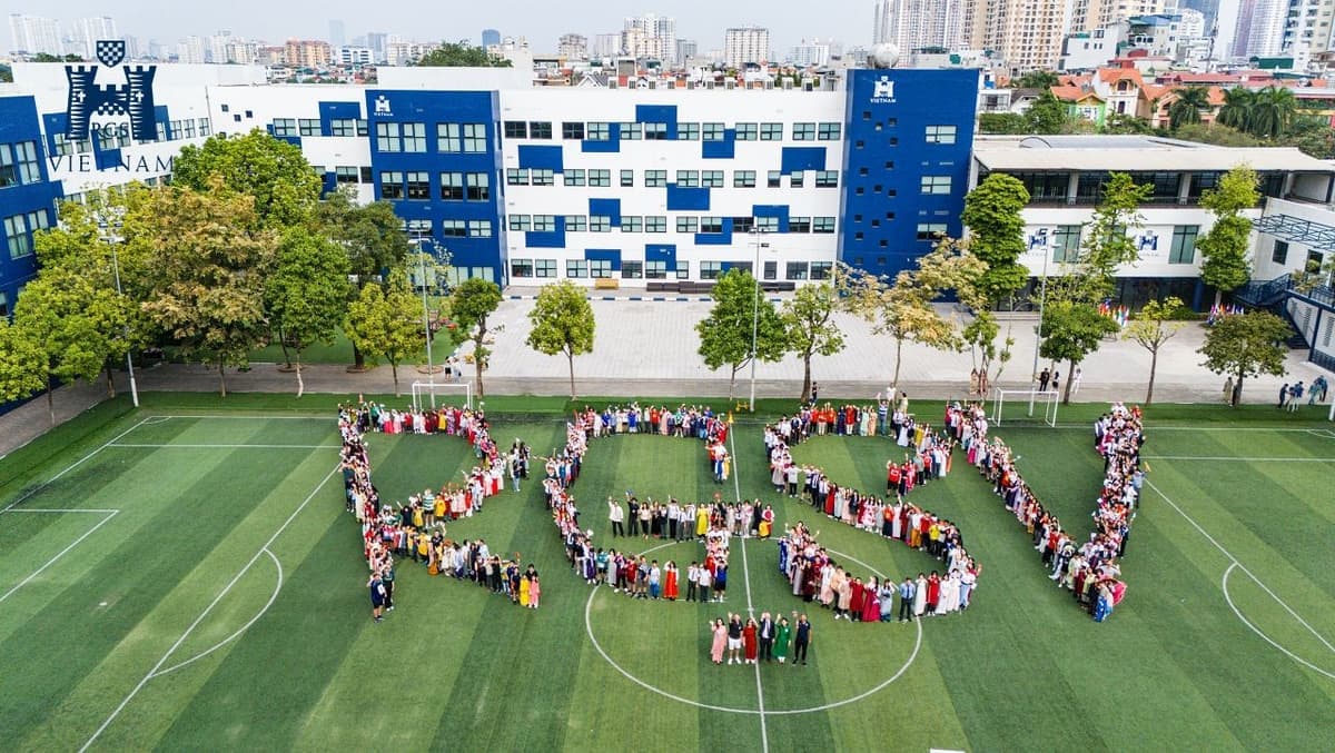 An aerial view of students spelling out the school’s initials on the sports field in front of the Reigate Grammar School Vietnam building