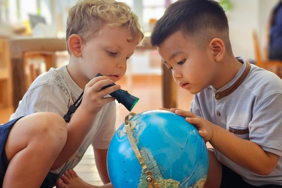 Two young children looking at a globe together at Sky International Preschool