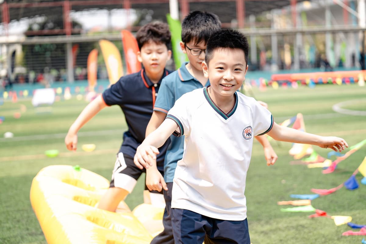 Primary students taking part in an outdoor sports day activity on a Wellspring Hanoi field